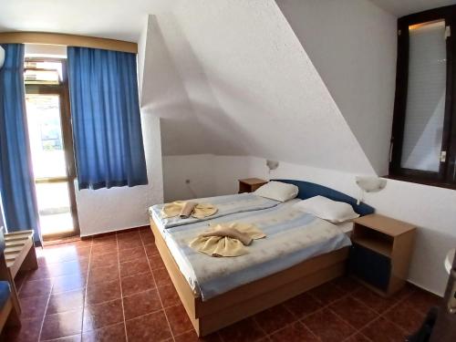a bedroom with a large bed with blue curtains at Guest House Olimpiya in Sveti Vlas