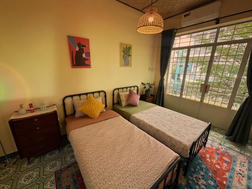 two beds in a room with a window at The Mê Linh House in Nha Trang