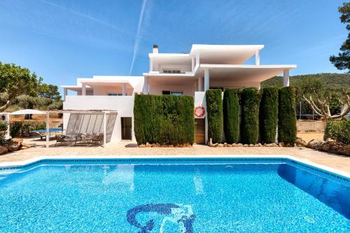 a villa with a swimming pool in front of a house at New! Villa Can Mila in Sant Joan de Labritja