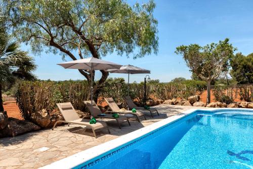 a swimming pool with chairs and an umbrella next to a pool at New! Villa Can Mila in Sant Joan de Labritja
