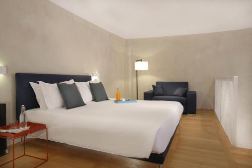 a bedroom with a large white bed and a chair at Hotel Palazzo Grillo in Genova