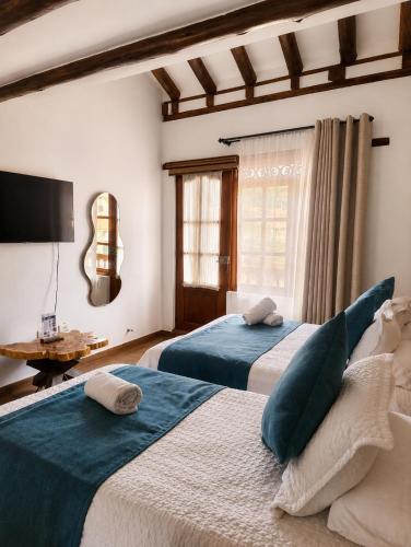 a bedroom with two beds and a tv on the wall at Hotel Boutique Cenit in Villa de Leyva
