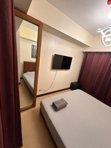 a bedroom with a mirror and a bed and a tv at Juja's place in Manila