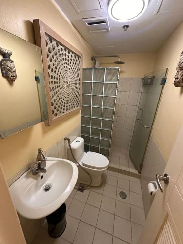 a bathroom with a sink and a toilet and a shower at Juja's place in Manila