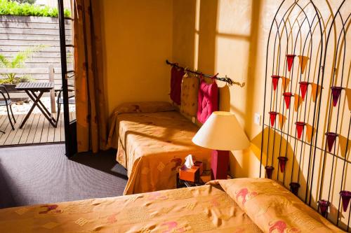 a room with two beds and a lamp and a balcony at La Bergerie Du Cap in Cap d'Agde