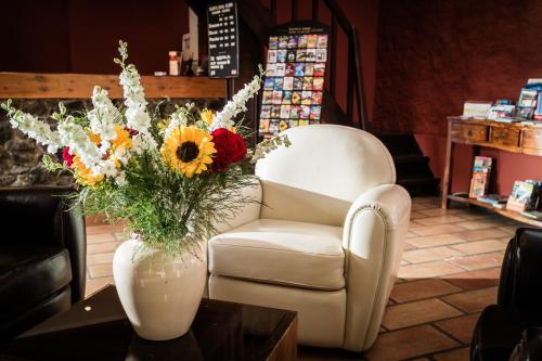 a living room with a chair and a vase of flowers at La Bergerie Du Cap in Cap d'Agde