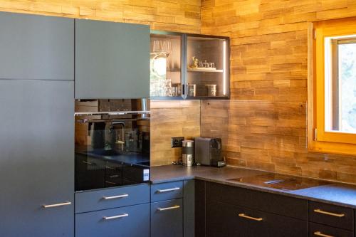 a kitchen with stainless steel appliances and wooden walls at Ferienwohnung Aegimatte in Ulrichen