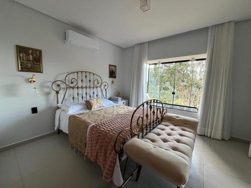 a bedroom with a bed and a chair and a window at Recanto Bougainville ST in Santa Teresa