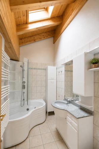 a bathroom with a tub and a shower and a sink at Residenz Château Leukerbad in Leukerbad