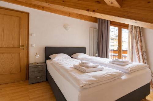 a bedroom with a large white bed with towels on it at Residenz Château Leukerbad in Leukerbad