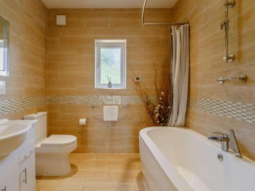 a bathroom with a tub and a toilet and a sink at 3 Bed in Kings Lynn oc-43259 in Dersingham