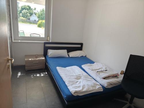 ein Schlafzimmer mit einem blauen Bett und einem Fenster in der Unterkunft imperial 1 in Leuenberg