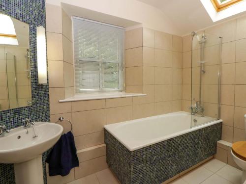 ein Badezimmer mit Badewanne und Waschbecken in der Unterkunft Ty Cellin in Ystrad Meurig