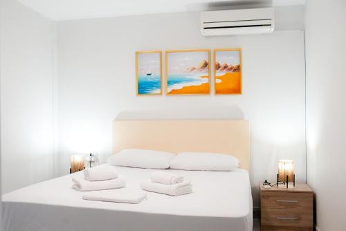a bedroom with a white bed with three paintings on the wall at Gridia Apartment in Chios