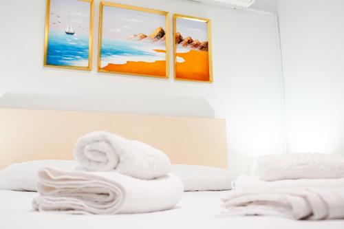 a white bedroom with two towels on a bed at Gridia Apartment in Chios