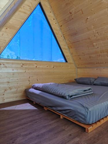 a bed in a wooden room with a large window at GiGi's Homestay & Coffee in Phú Xá