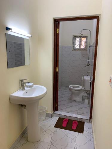 a bathroom with a sink and a toilet with pink slippers at Iconic lux living in Malindi