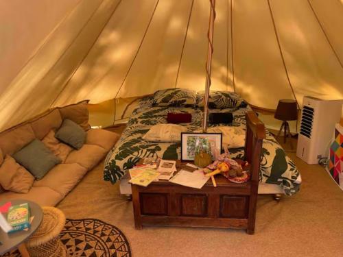 a bedroom with a bed and a couch in a tent at Tente en jardin in Boulazac