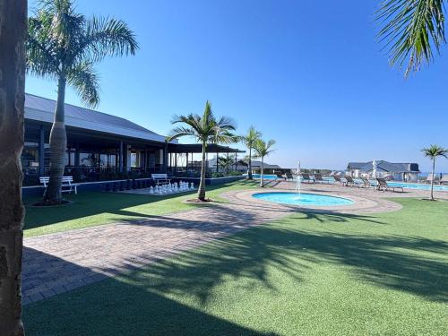a resort with a swimming pool and palm trees at Shoreline Sanctuary! in Ballito