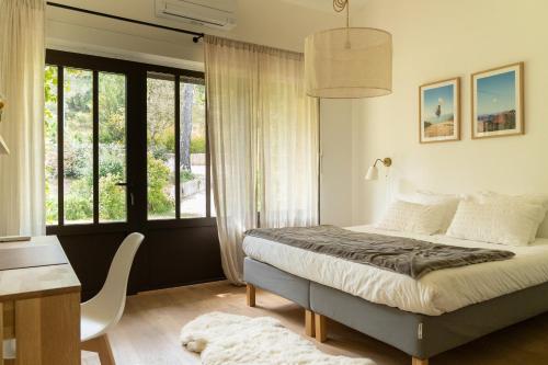 a bedroom with a bed and a desk and windows at La Bergerie du Roy-Chambres D'hôtes- in Rognes