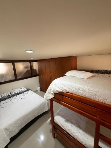 a bedroom with two twin beds with white sheets at Hostal Brooklyn in Ipiales