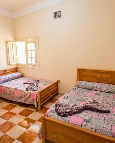a bedroom with two beds and a checkered floor at شاليه العميد chalet in Marsa Matruh