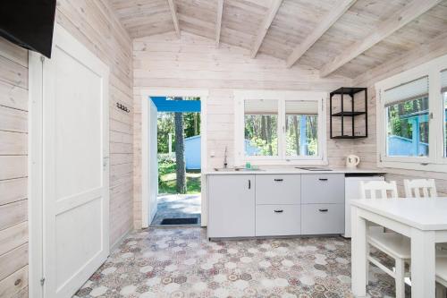 a kitchen with white cabinets and a table at Greckie Domki ZEUS in Stegna