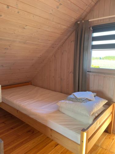 a bed in a wooden cabin with a window at Domki Na Skraju in Stegna