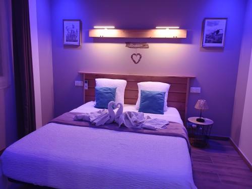 a purple bedroom with a bed with a towel on it at L'Ardétente - Le cosy, Piscine et SPA en Ardèche, Adults only in Lussas