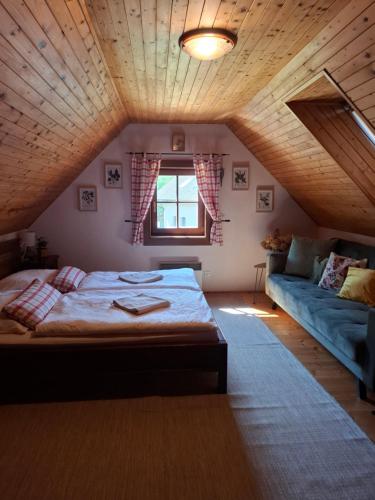 a bedroom with a bed and a couch in a attic at Chata DOBROTKA in Liptovský Mikuláš