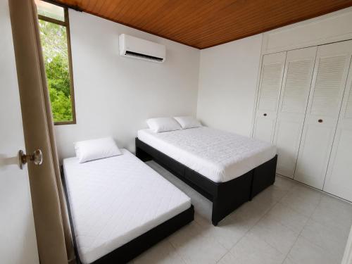 two beds in a room with white walls and a window at APTO CENTRO DE MELGAR CON PISCINA EN CONJUNTo in Melgar