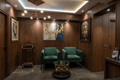 a waiting room with two green chairs and a portrait at Hotel Nexus Cyber Hub Near Rapid Metro & Ambience Mall in Gurgaon