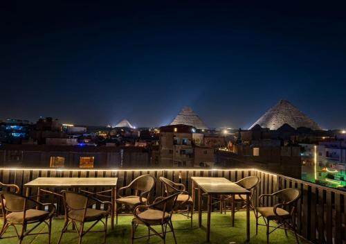 a group of tables and chairs on a balcony at night at Nefertari Pyramids View Inn in Cairo