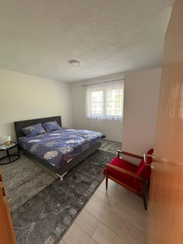a bedroom with a bed and a red chair at Apartman HUSEIN in Jajce