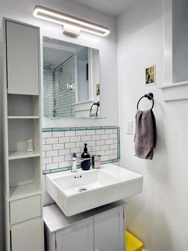 a bathroom with a white sink and a mirror at The Orange Door Bungalow- 2-BR w private yard, walkable to cafes & restaurants, 10 min to DT in Vancouver