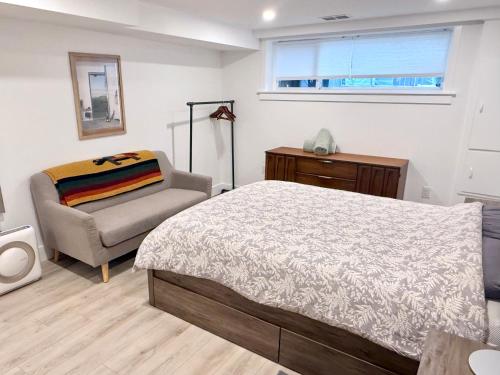 a bedroom with a bed and a chair and a window at The Orange Door Bungalow- 2-BR w private yard, walkable to cafes & restaurants, 10 min to DT in Vancouver