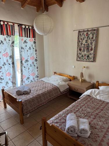 a bedroom with two beds and a window with curtains at Villa Trifylli in Mesimvría