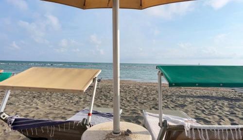 two chairs under an umbrella on the beach at Alloggio turistico di Stefano in Lido di Ostia