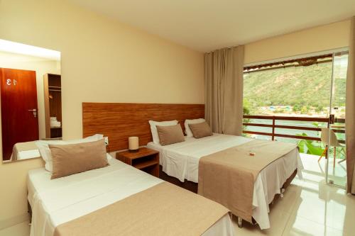 a hotel room with two beds and a balcony at Pousada Porto de Piranhas in Piranhas