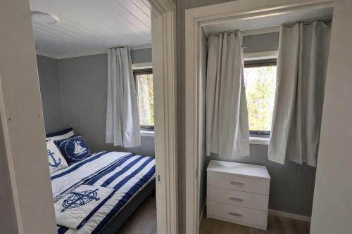 a small bedroom with a bed and two windows at Oslofjord Sea View in Hvitsten