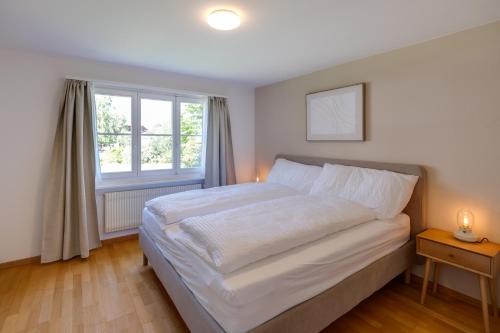 a bedroom with a large white bed and a window at Trois Lacs Suites in Erlach