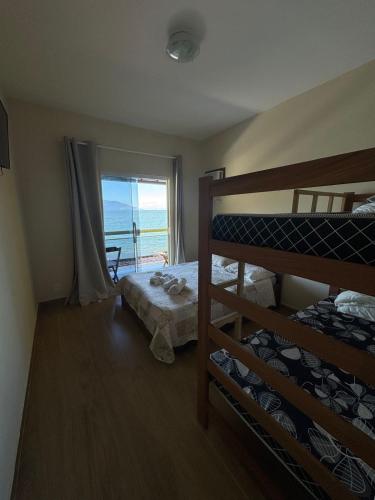 a bedroom with two bunk beds and a window at Pousada Amendoeira in Mangaratiba