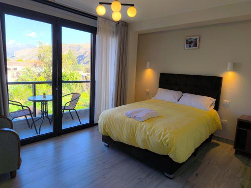 a bedroom with a bed and a balcony with a table at PACHAMAMA APARTMENt, MODERNO, ACOGEDOR Y CON VISTA PANORAMICA in Urubamba
