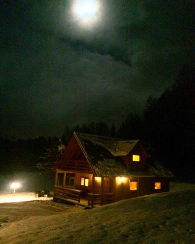 a cabin at night with the moon in the sky at Mana Village - Jacuzzi & Sauna in Barłomino