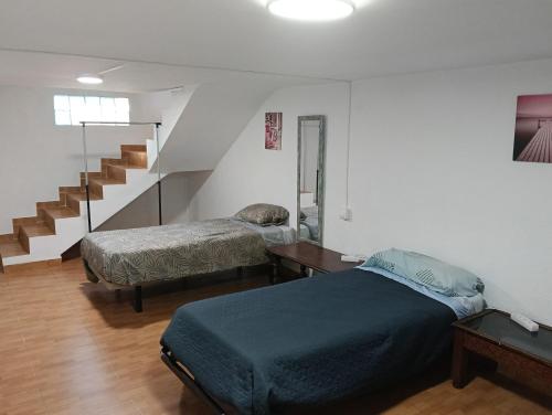 a bedroom with two beds and a stair case at Casita del Romero Ronda in Ronda