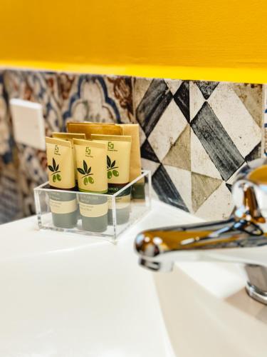 a bathroom with three coffee cups on a tray next to a sink at B&B Il Grande Cipresso Recanati in Castelnuovo