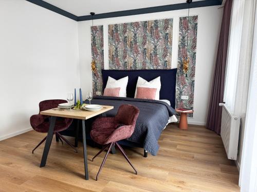 a bedroom with a bed and a table and chairs at ME LIVING Villa am Kurpark - Design Apartments in Bad Salzuflen