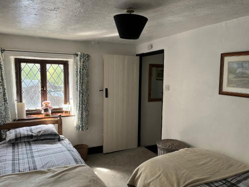 a bedroom with a bed and a window at The Eliot Cottage in South Petherwin