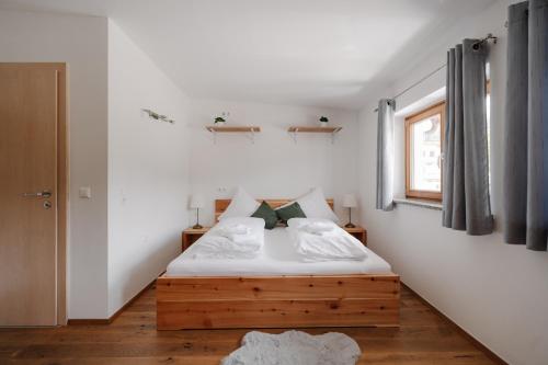 a bedroom with a bed with white walls and a window at Zimmer Zur Säge in Kötschach