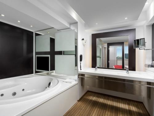 a bathroom with a tub and a large mirror at Novotel Bucharest City Centre in Bucharest